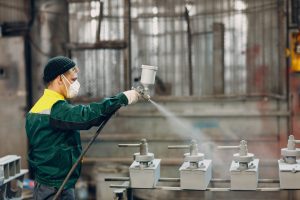 worker applying powder coat to metal parts in Reno, NV